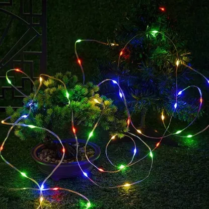 Rainbow-colored RGB string lights decorating garden shrubs at night